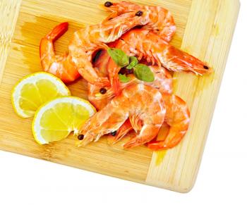 Shrimp on a wooden board with slices of lemon and basil isolated on white background
