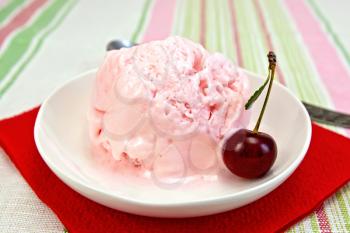 Cherry ice cream in a dish on a red paper napkin on a linen tablecloth background