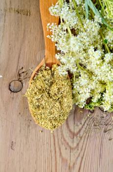 Wooden spoon with dried flowers of meadowsweet, a bouquet of fresh flowers of meadowsweet on a wooden board