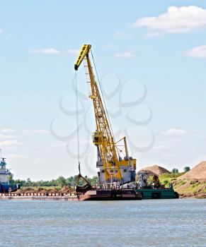 Loading sand with the help of a crane on a barge. River White, Russia