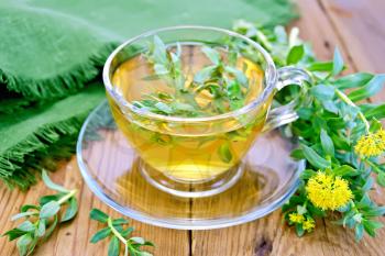 Herbal tea in a glass cup with flowers Rhodiola rosea, green cloth on a wooden board