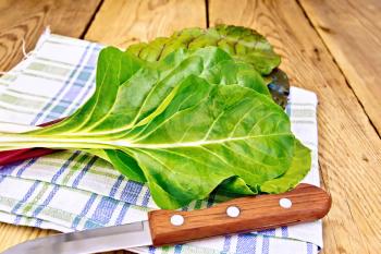 A beam of red and yellow chard, knife, napkin on a wooden boards background