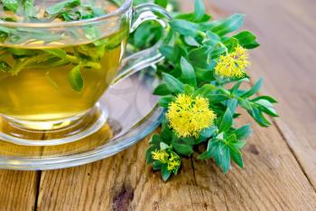 Flowers Rhodiola rosea, an herbal tea in a glass cup on a wooden boards background
