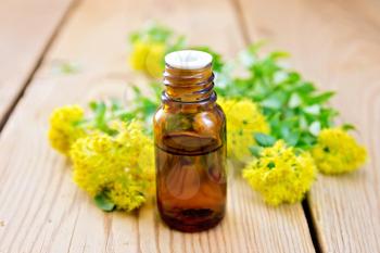 The oil in the bottle, flowers and leaves Rhodiola rosea on a wooden boards background