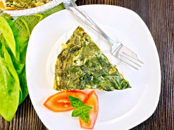 Celtic cake with spinach, tomatoes, oatmeal and eggs, basil in white plate on the background of wooden boards on top