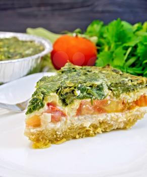 Celtic cake with spinach, tomatoes, oatmeal and eggs in a white plate in a baking dish from a foil, a napkin, fork on the background of wooden boards