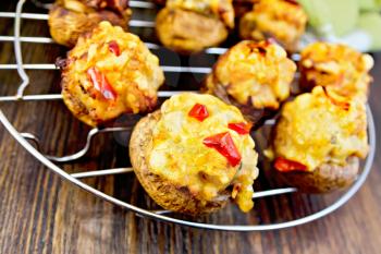 Mushrooms stuffed with meat and pepper on a metal grid, green cloth on a wooden boards background