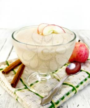 Air apple jelly in a glass bowl, red apples and cinnamon on a towel on the background light wooden boards