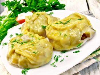 Steam meat pies and potatoes, dill in a dish on a kitchen towel, cream sauce, parsley on a wooden boards background