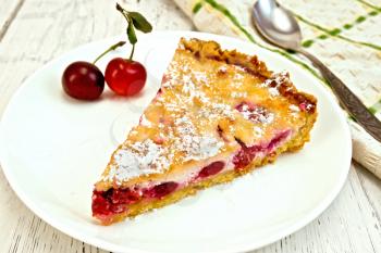 Pie with cherries and sour cream in a dish, towel with a spoon on a background of wooden boards