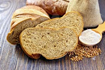 Slices of buckwheat bread, a bag of buckwheat, buckwheat flour in a spoon on a wooden boards background