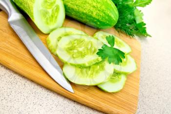 Cucumbers cut with parsley and a knife on a wooden board, dill on the background of a granite table