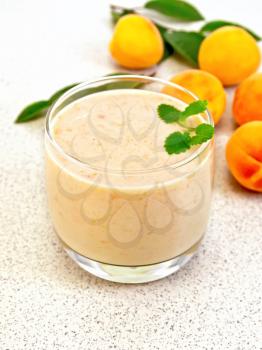 One glass of milkshake with apricots, mint on the background of the stone table