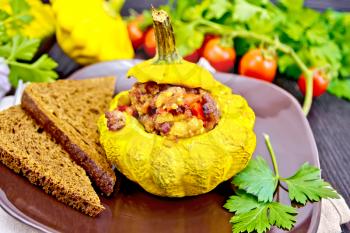Squash yellow stuffed with meat, tomatoes and peppers, bread in plate, tomatoes, parsley on a dark wooden board