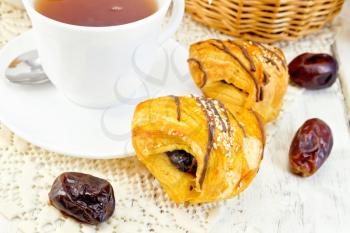 Cookies with dates, tea in a cup on a napkin on the background light wooden boards
