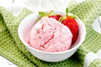Ice cream strawberry in a white bowl with berries on a green napkin against a light wooden board