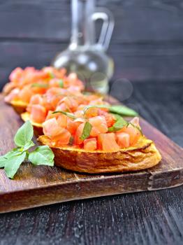 Bruschetta with tomatoes and basil on a black wooden board background