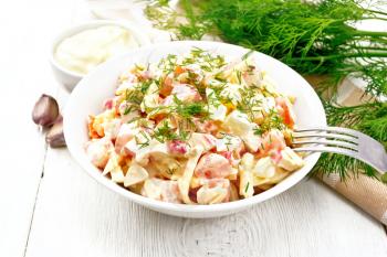 Salad of crab sticks, cheese, garlic, eggs and tomatoes, dressed with mayonnaise in a plate, kitchen towel and parsley on the background of a light wooden board