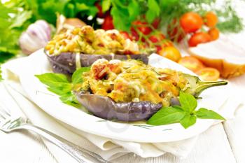 Stuffed eggplant with smoked brisket, tomatoes, onions, carrots with garlic, cheese and herbs in a plate on a towel on a background of light wooden board
