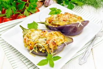 Stuffed eggplant with smoked brisket, tomatoes, onions, carrots with garlic, cheese and herbs in a plate on a towel on wooden board background
