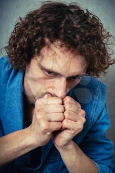 curly-haired man praying, clasped his hands together