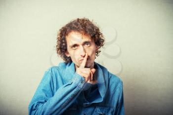 curly-haired man asks quiet and keeps his finger to his mouth