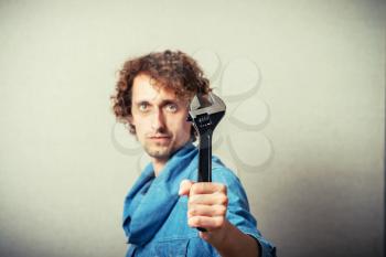 Curly man with a wrench. On a gray background.