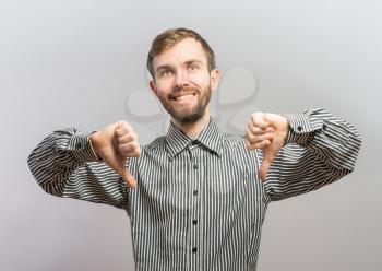 Closeup portrait of sarcastic young man showing two thumbs down sign hand gesture, happy that someone made mistake, lost, failed isolated white background. Negative emotion, facial expression feelings