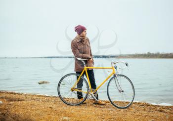 a young man with a bicycle near the shore