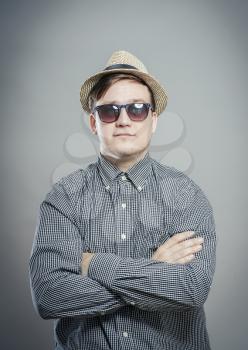 Portrait of handsome serious man in hat and glasses standing