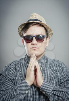 Portrait of handsome serious man in hat and glasses standing