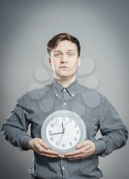 Portrait Of A Young Man Holding A Clock On Gray Background