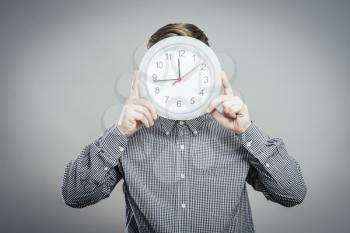 man  holding big clock covering his face over white