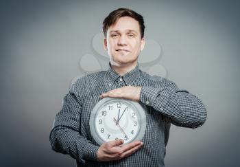 Young Man Holding A Clock On Gray Background