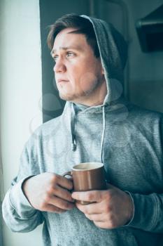 Handsome guy with cup of tea in the hood
