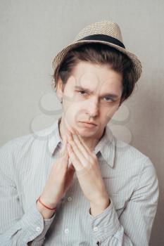 young man  in hat showing clasped hands on top isolated grey wall background