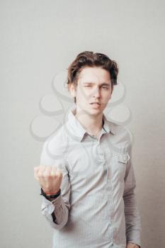 Closeup portrait, hostile angry irritated upset young man raising shaking fists at you to camera gesture. Negative human emotion facial expression feelings conflict