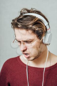 Man in headphones listening to music. On a gray background.