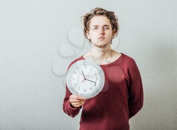 portrait of a man holding a clock against a grey background