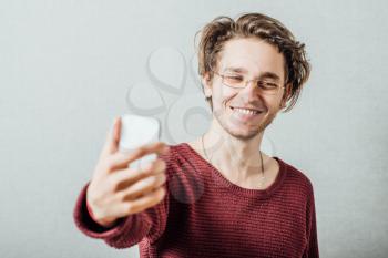 Cheerful selfie. Cheerful young man  making photo of himself while standing against grey background