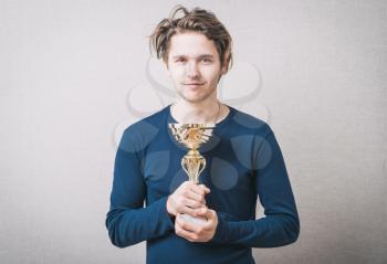 young man holding a prize cup and happy
