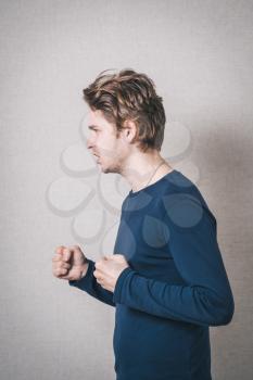 young man angry, on a gray background.