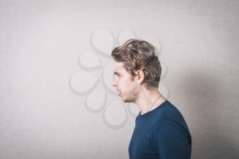 A man looks forward with disgust profile. Gray background.