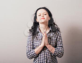 Closeup portrait of a young woman praying, isolated on a gray background