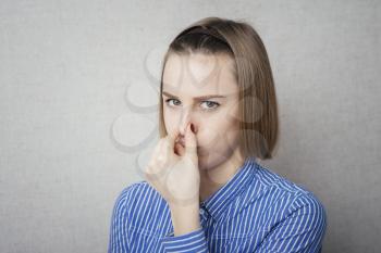 Woman disgusted by bad smell holding her nose