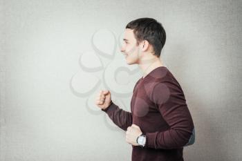portrait of young man winner gesture against a grey background