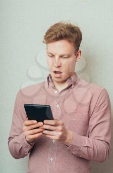 young man with tablet in hand surprised