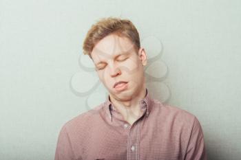 Closeup portrait, funny annoyed young childish rude bully man sticking his tongue out at you camera, gray  background. Negative emotion facial expression feelings, signs, symbols