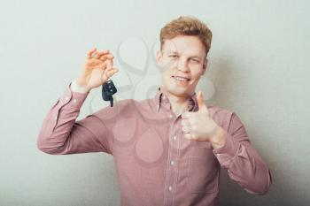 Young man . Holding a car keys with his thumb up also