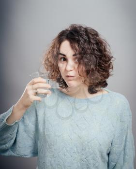 Young woman posing on isolated studio background, hold water glass. Beautiful girl portrait. Female model poses.